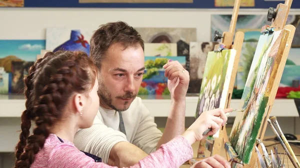 Mature male painter artist helping his cute daughter with a painting — Stock Photo, Image