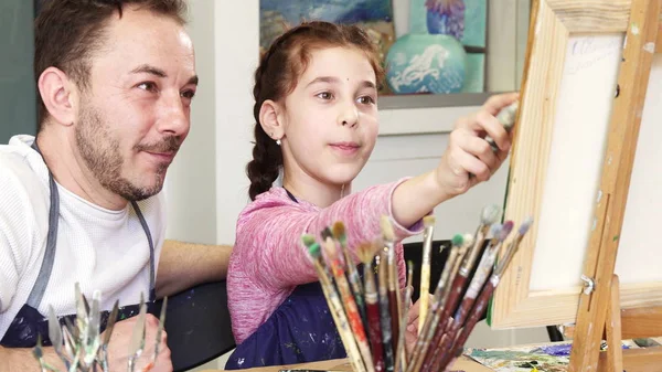 Orgulhoso pai assistindo sua linda filha pintando um quadro — Fotografia de Stock