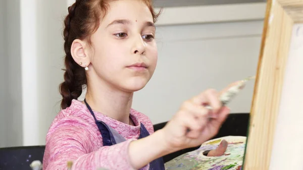 Menina bonita segurando paleta pintando um quadro — Fotografia de Stock