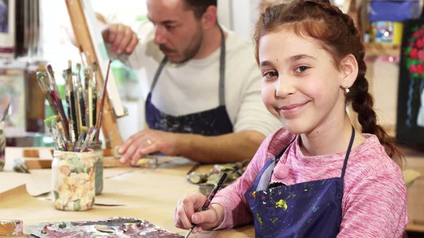 Menina litlle feliz bonito sorrindo para a câmera enquanto desenha um quadro — Fotografia de Stock