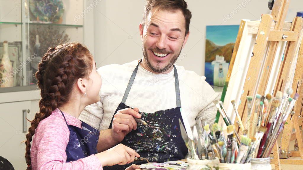 Father and daughter enjoying painting together high fiving at art studio