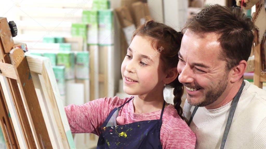 Happy father and daughter taking selfies at art studio while painting