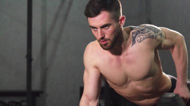 Genç gömleksiz erkek atlet spor salonunda geri egzersiz yapıyor odaklı