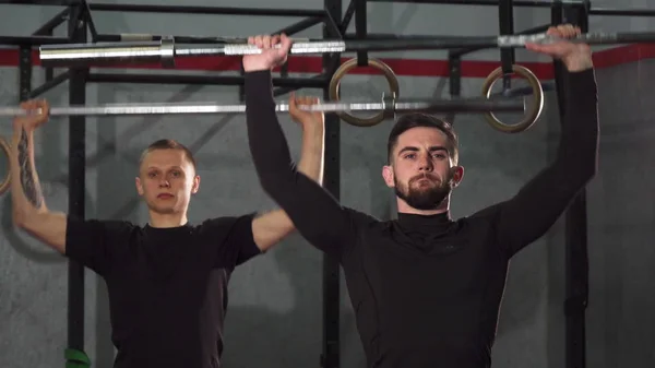 Male crossfit athletes warming up at the gym lifting barbells
