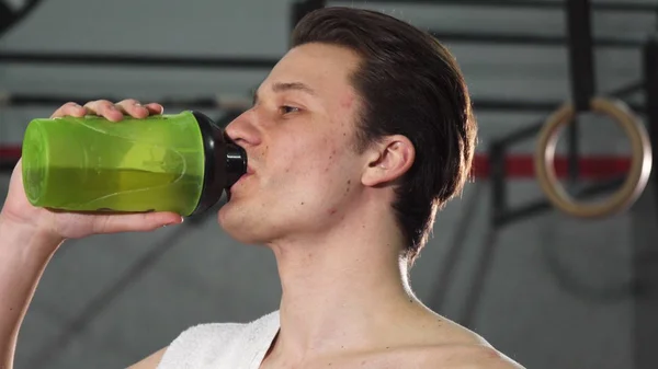 Junger männlicher Athlet lächelt fröhlich und trinkt Wasser — Stockfoto