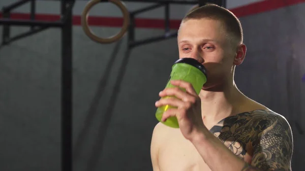 Young cheerful sportsman drinking water after a workout — Stock Photo, Image