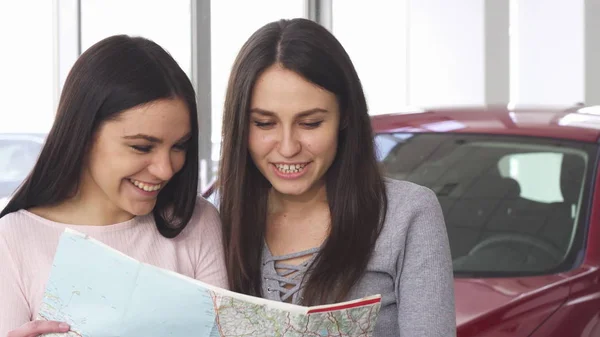 Zwei schöne Freundinnen auf der Suche nach einem Reiseziel auf einer Karte — Stockfoto