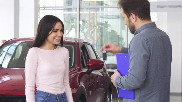 Wunderschöne glückliche Frau schüttelt Autohändler die Hand, nachdem sie Autoschlüssel erhalten hat — Stockfoto