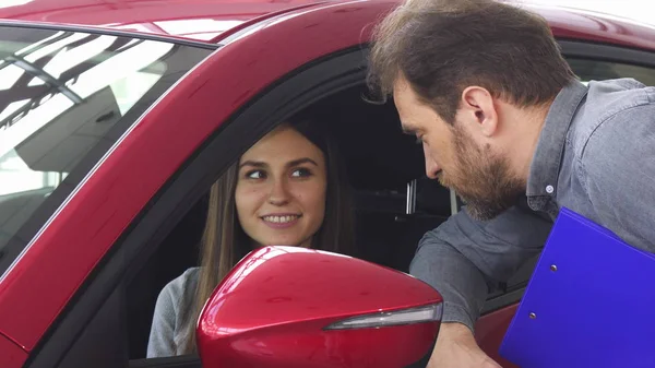 Attraktive Frau sitzt in einem neuen Auto und spricht mit dem Verkäufer — Stockfoto