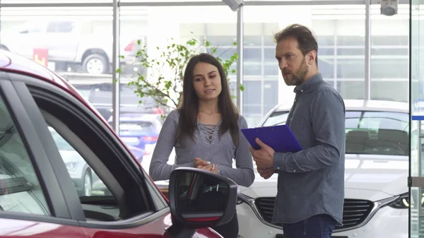 Reifer Verkäufer im Gespräch mit seiner Kundin, die ihr ein Auto anbietet — Stockfoto
