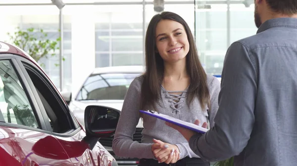 Junge Frau im Gespräch mit dem Verkäufer im Autohaus — Stockfoto