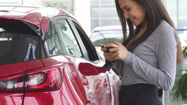 Schnappschuss einer Frau mit ihrem Smartphone, das in der Nähe ihres Autos steht — Stockfoto