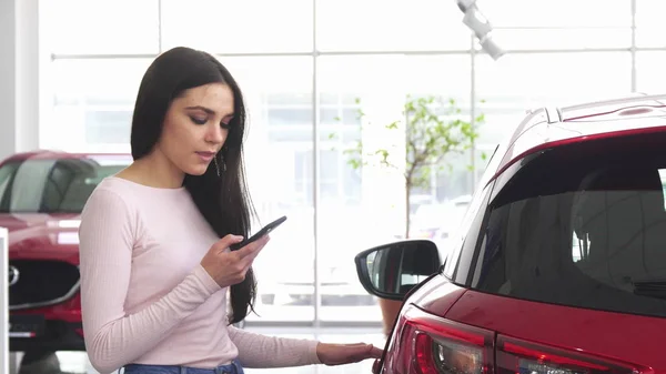 Glückliche Frau mit Smartphone im Autohaus — Stockfoto
