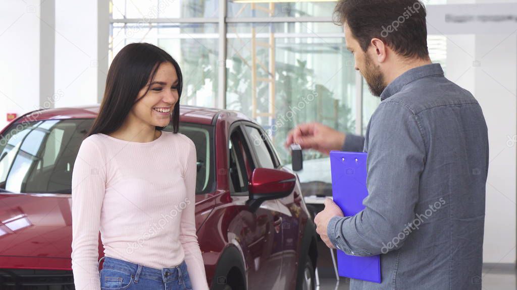 Gorgeous happy woman shaking hands with car dealer after receiving car keys