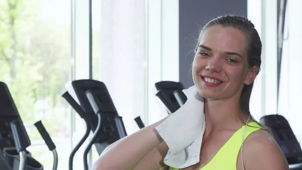 Bella donna che si pulisce il collo con un asciugamano dopo l'allenamento in palestra — Foto Stock