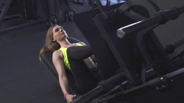 Mujer atlética haciendo ejercicio en la máquina de prensa de piernas en el gimnasio — Foto de Stock