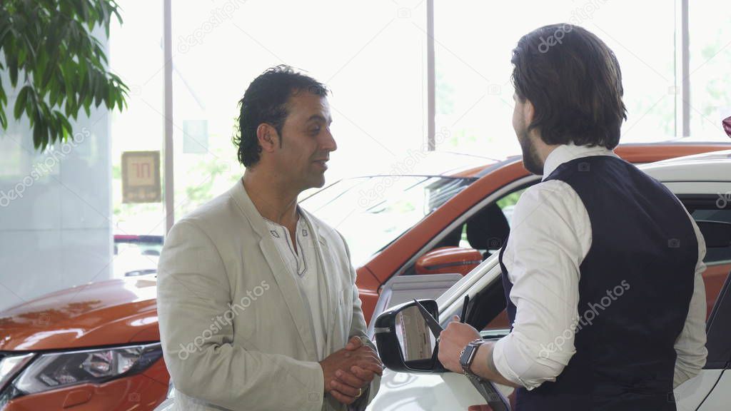 Handsome mature man choosing a new automobile at the dealership