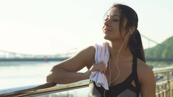 Happy young healthy woman relaxing after workout outdoors in the morning