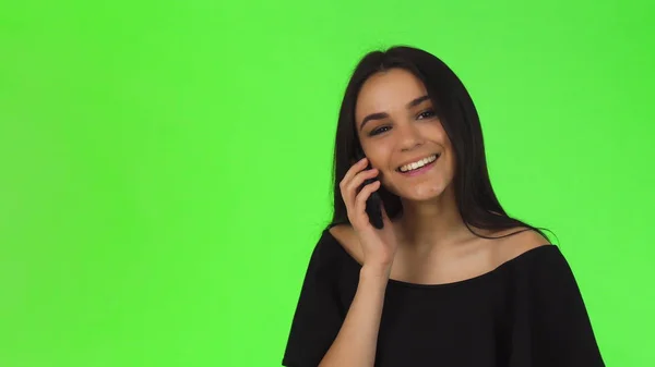 Jovem atraente em vestido preto falando ao telefone — Fotografia de Stock