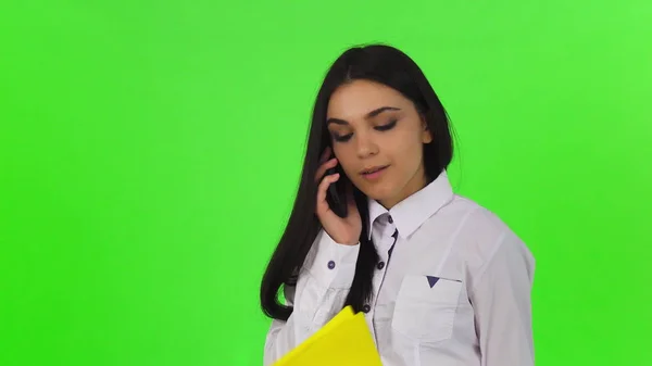 Atrakcyjna kobieta rozmawia przez telefon, przytrzymanie schowka — Zdjęcie stockowe