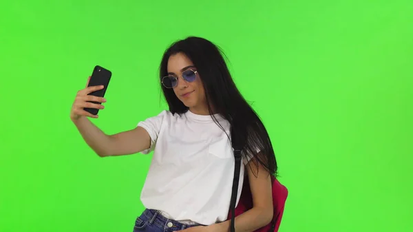 Encantadora estudiante con una mochila tomando selfies con su teléfono inteligente —  Fotos de Stock