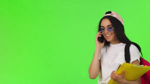 Estudante alegre falando ao telefone, segurando seus livros — Fotografia de Stock