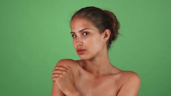 Attraente giovane donna con pelle perfetta posa elegantemente su sfondo verde — Foto Stock