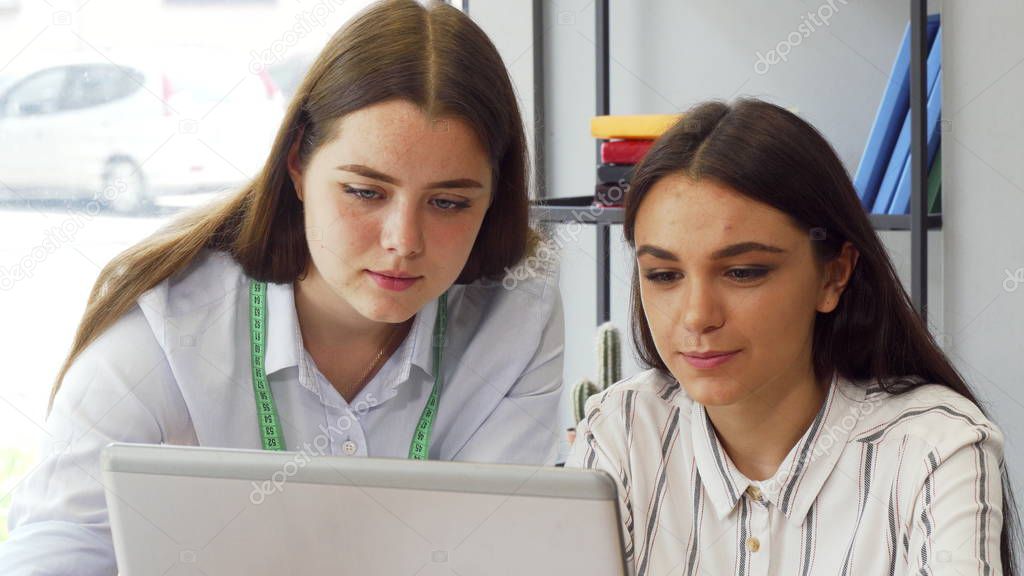 Two young businesswomen working on a computer together