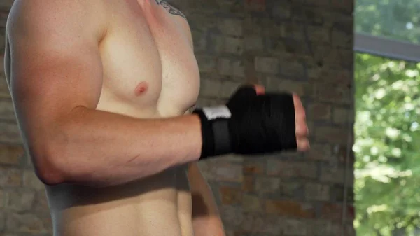 Poderoso luchador masculino envolviendo sus nudillos preparándose para luchar — Foto de Stock
