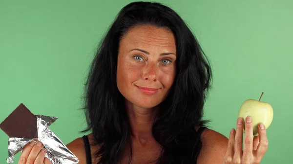 Çekici kadın çikolata ve bir elma arasında seçim yapma