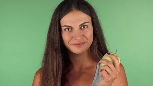 Здорова жінка вибирає зелене яблуко над шоколадним баром — стокове фото