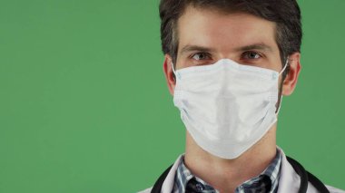 Erkek doktor sevinçle gülümseyen tıbbi maske takıyor
