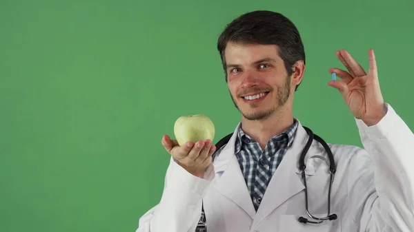 Alegre doctor masculino sosteniendo la píldora de la vitamina y una manzana — Foto de Stock