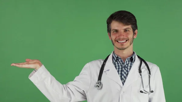 Médico masculino sonriendo sosteniendo espacio de copia en su mano —  Fotos de Stock