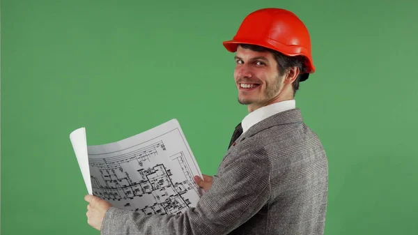 Knappe bebaarde ingenieur glimlachen naar de camera terwijl het onderzoeken van blauwdrukken — Stockfoto