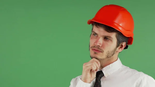 Bello maschio costruttore in un hardhat guardando lontano pensieroso — Foto Stock