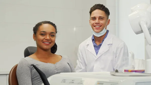 Wanita muda ceria dan dokter giginya tersenyum ke kamera — Stok Foto