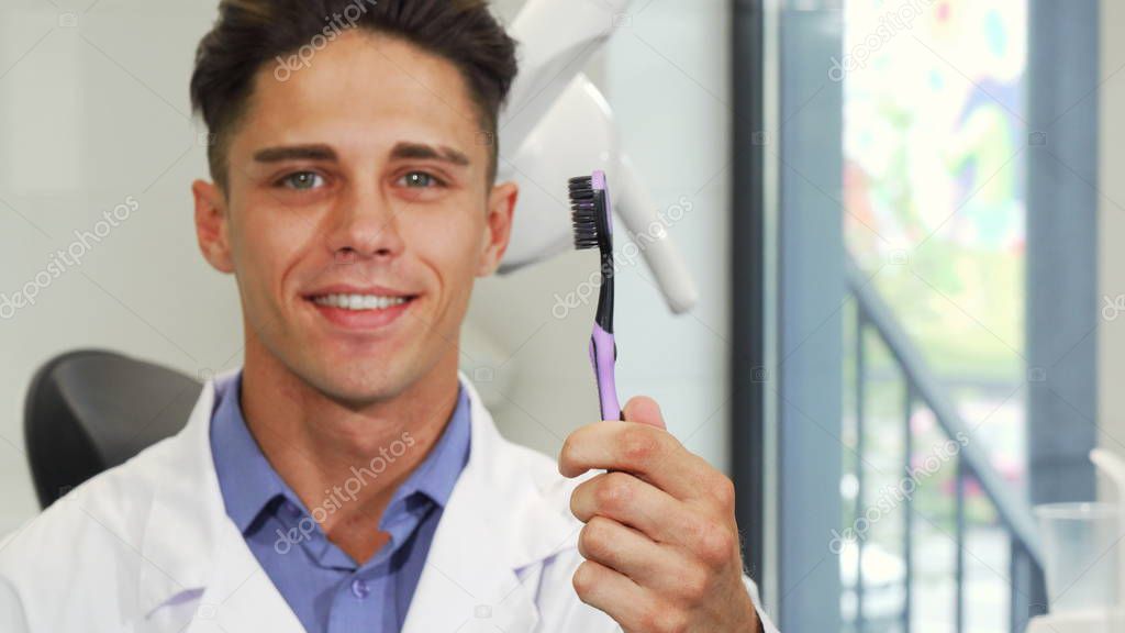 Attractive male dentist smiling holding a toothbrush