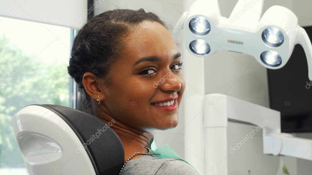 Attractive female patient smiling to the camera sitting in a dental chair