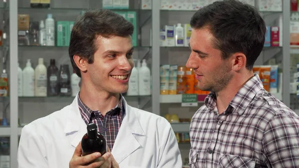 Hombre guapo hablando con un farmacéutico en la farmacia —  Fotos de Stock