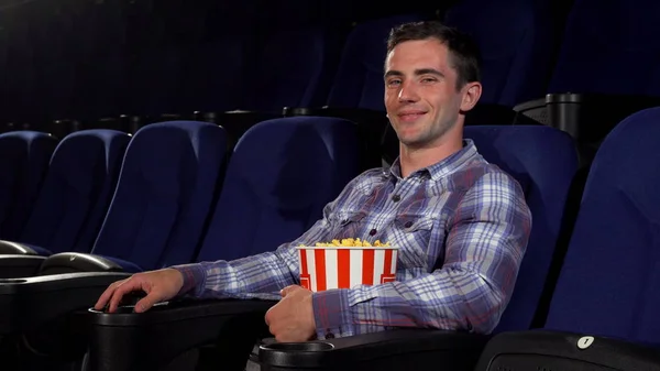 Homem bonito feliz sorrindo alegremente sentado no cinema — Fotografia de Stock