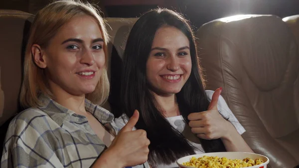 Mulheres bonitas mostrando polegares para cima enquanto assiste filme no cinema — Fotografia de Stock