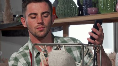 Yakışıklı erkek heykeltıraş çalışırken onun akıllı telefon kullanma