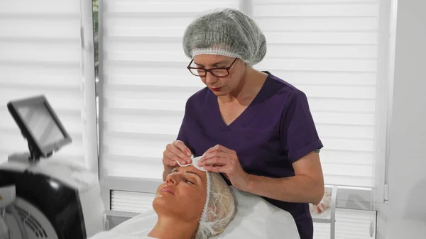 Επαγγελματική cosmetologist χρησιμοποιώντας μαξιλάρια βαμβάκι ενώ καθαρίζετε το πρόσωπό του πελάτη — Φωτογραφία Αρχείου