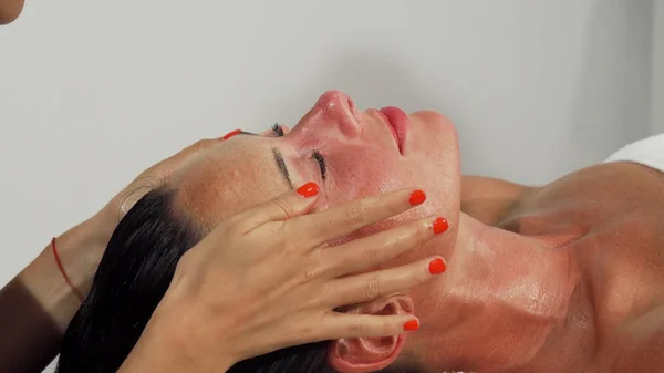Mujer madura sonriendo mientras recibe masaje facial — Foto de Stock
