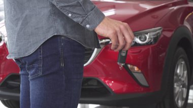 Arabanın anahtarlarını bir otomatik önünde ayakta tutan bir adam çekim kırpılmış