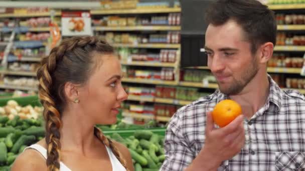 Alegre jovem casal cheirando laranjas ao comprar comida — Vídeo de Stock