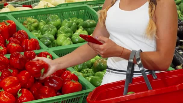 Женщина с помощью смартфона во время покупок в супермаркете — стоковое видео