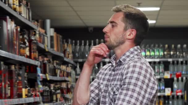 Hombre guapo examinando bebidas para la venta en el supermercado — Vídeos de Stock