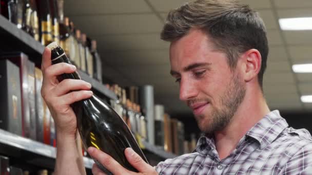 Handsome man smiling to the camera holding wine bottle — Stock Video